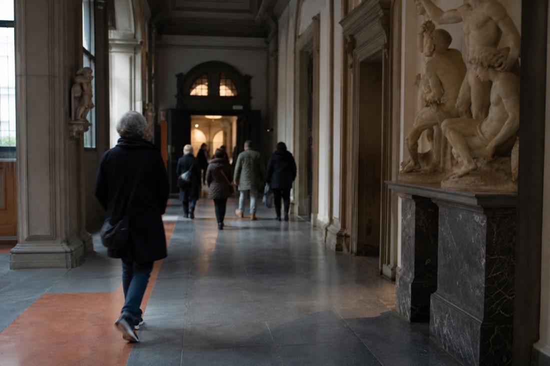 A quiet first-slot morning inside the Accademia with a handful of early visitors near the entrance corridor in Florence