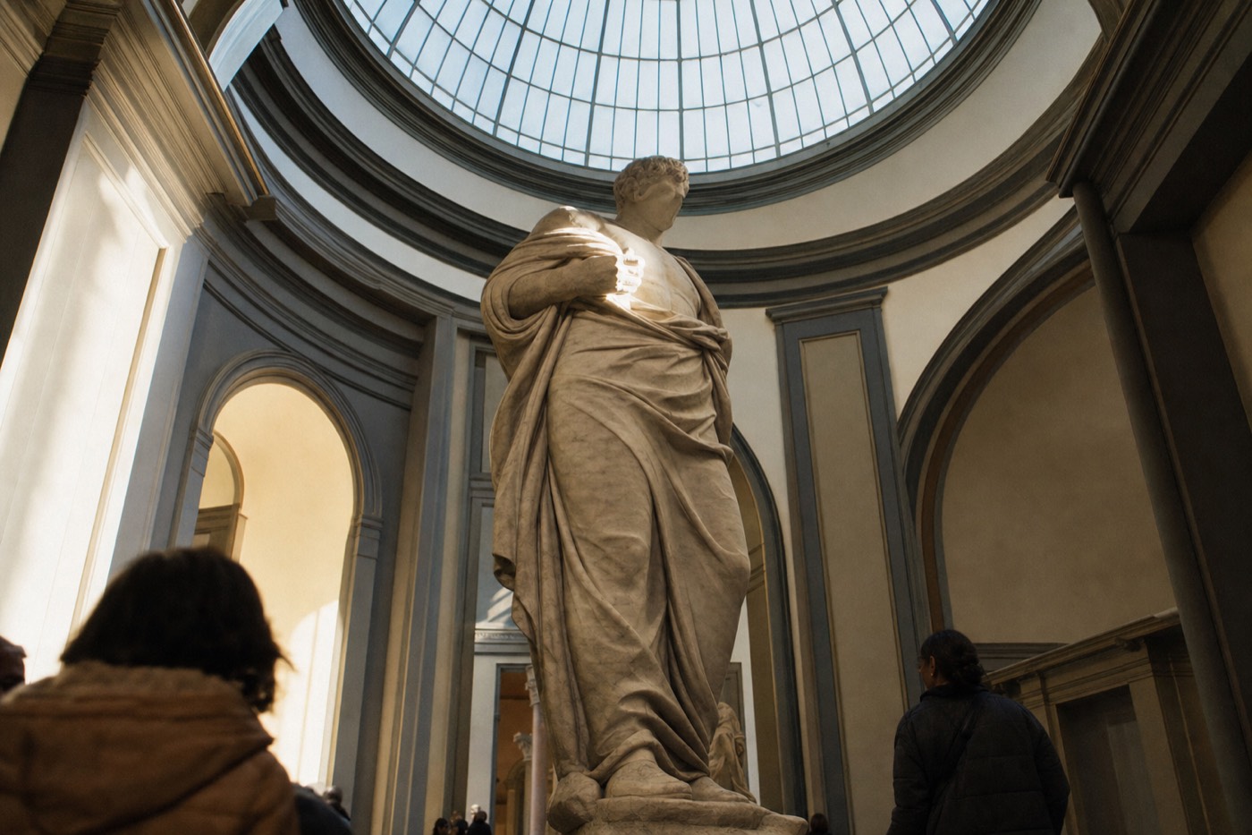Michelangelo's marble David standing under the domed skylight of the Accademia Gallery tribune in Florence, seen from below