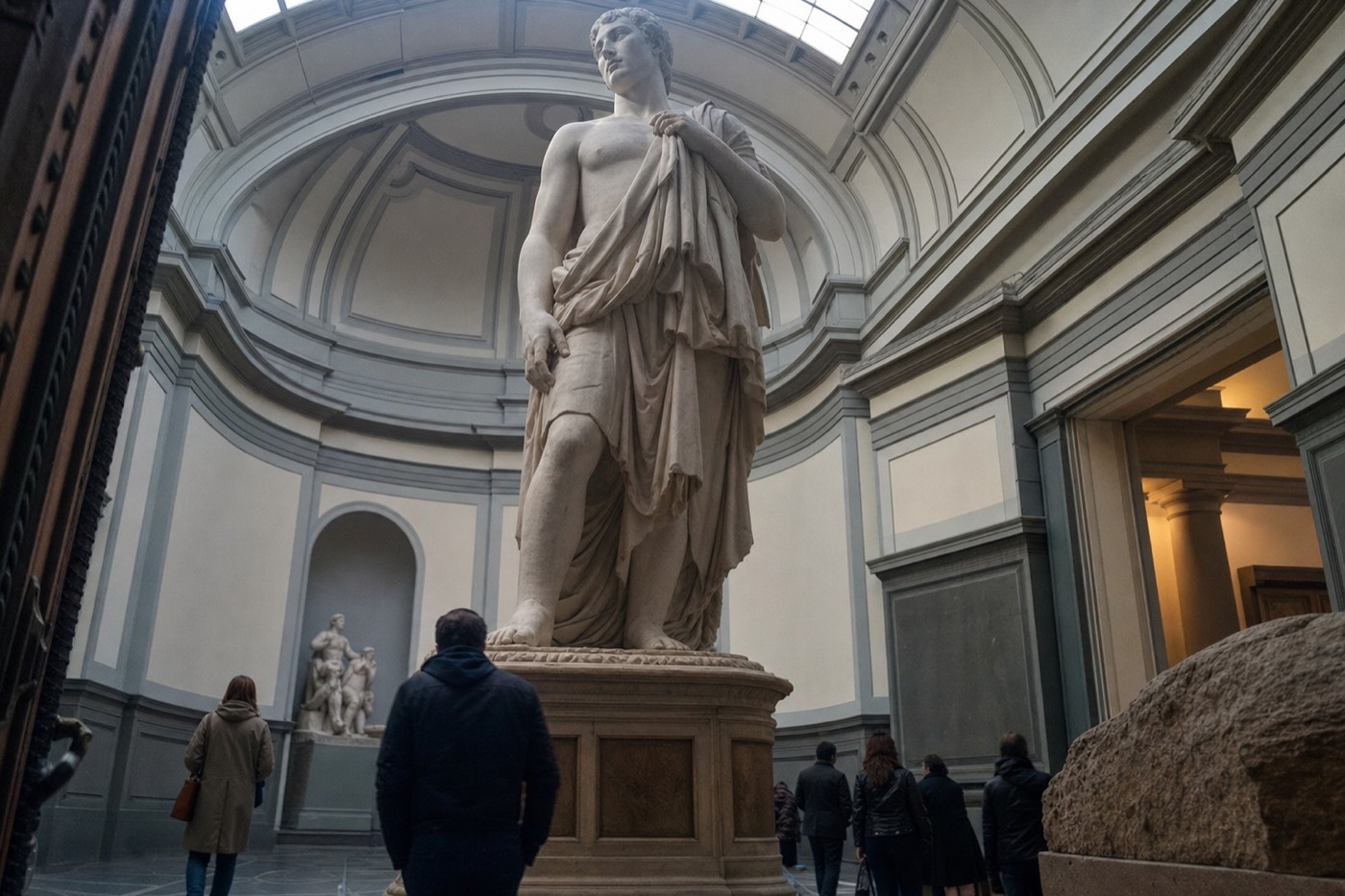 Michelangelo's David standing under the domed skylight of the Tribune in the Accademia Gallery in Florence, seen from the foot of the plinth