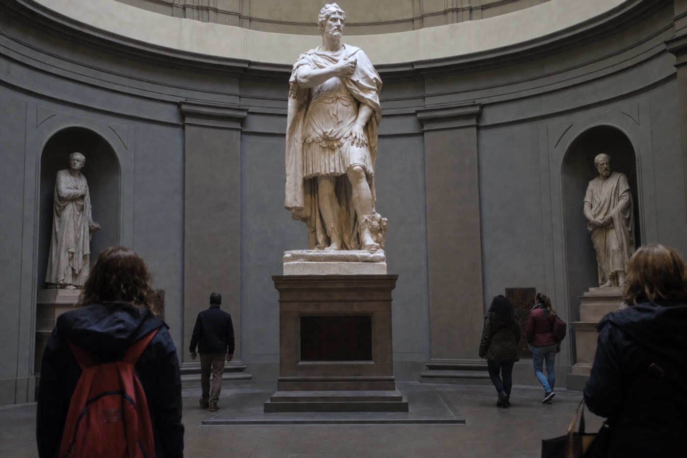 Michelangelo's marble David lit from above in the Accademia Gallery tribune in Florence, the pale stone glowing against a soft dome