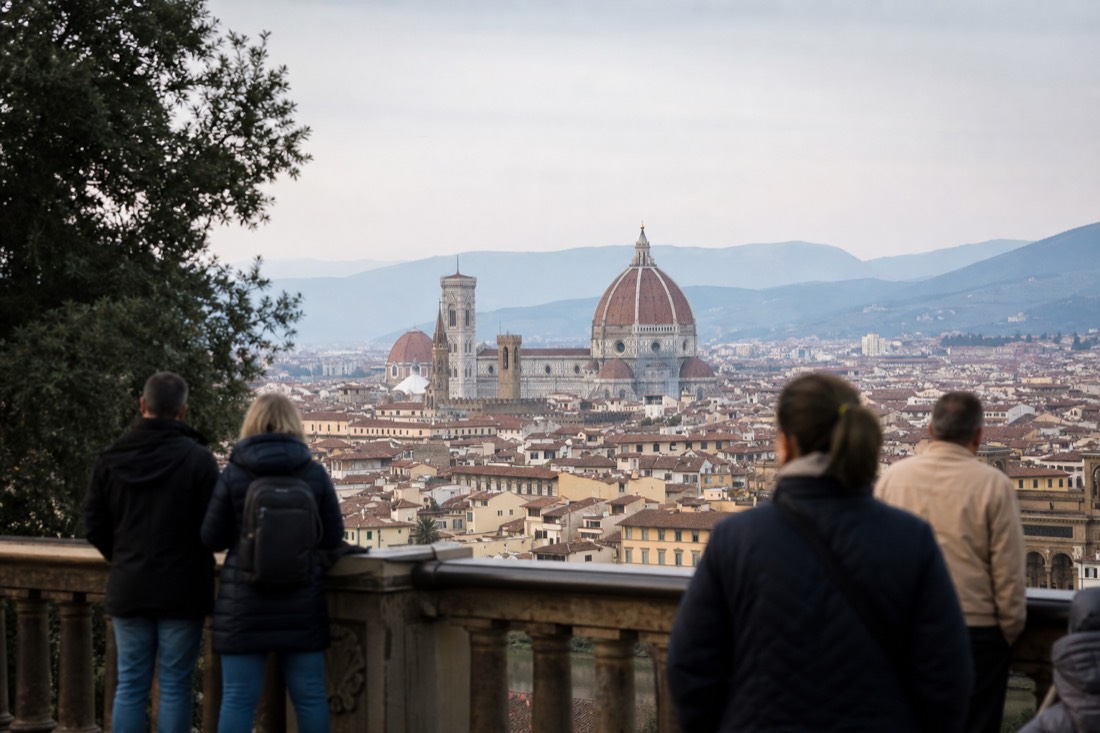 A wide view over Florence rooftops toward the red Duomo dome under a clear morning sky